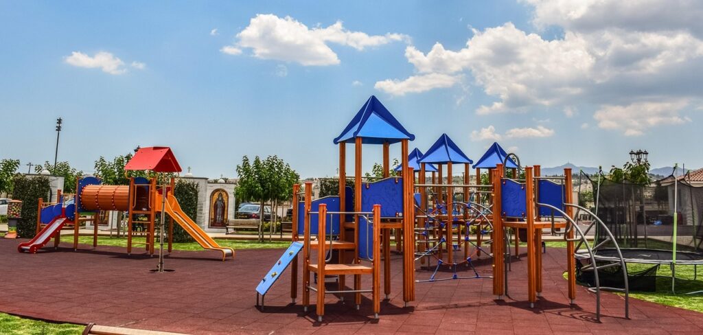 Rodzice obserwujący dzieci na gumowej nawierzchni placu zabaw w parku w Parmie