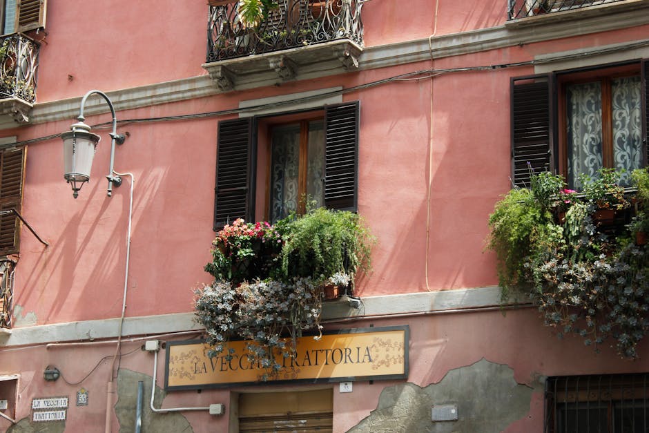 La Vecchia Trattoria sign on pink Parma facade with overflowing flower boxes