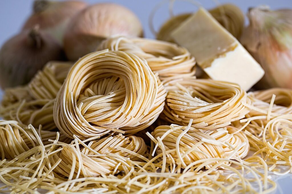 Fresh pasta nests with wedge of cheese and onions, ready to cook