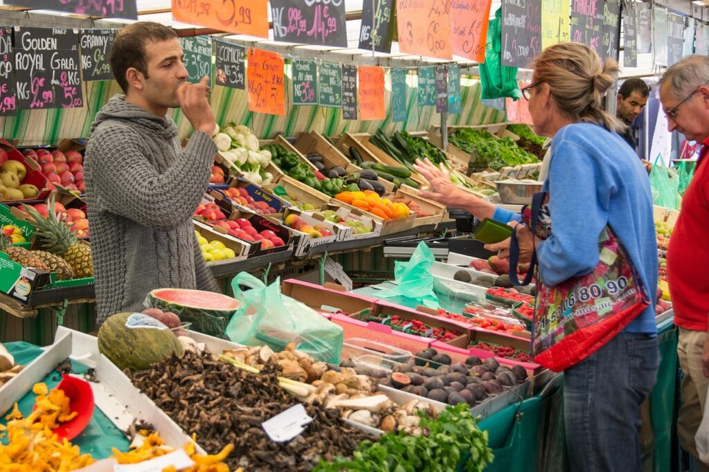 Étal coloré de fruits et légumes au marché de Parme, clients discutent