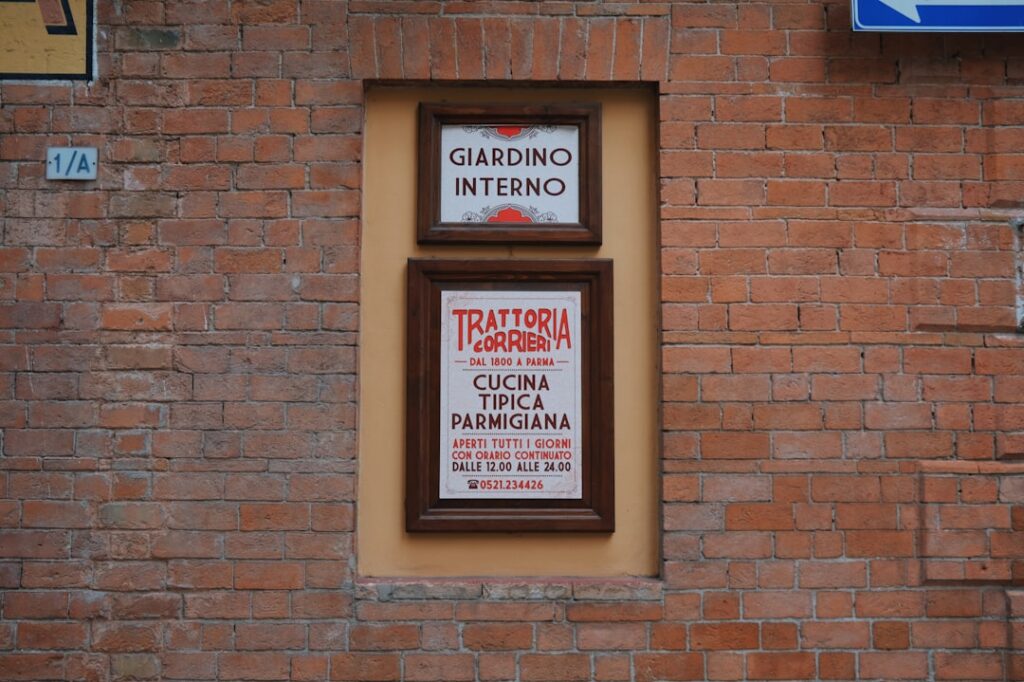 Schild der Trattoria Corrieri an Backsteinwand in Parma