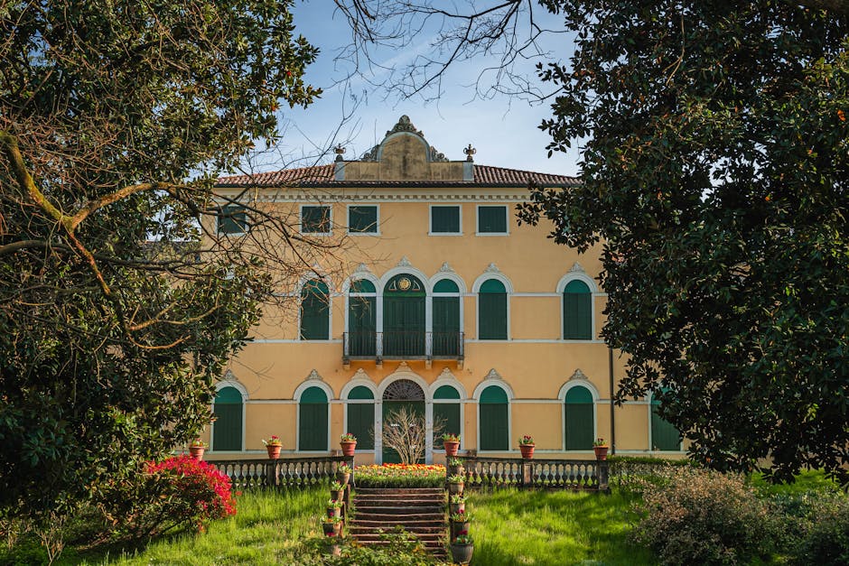 Villa gialla con persiane verdi e giardino tra alberi a Parma
