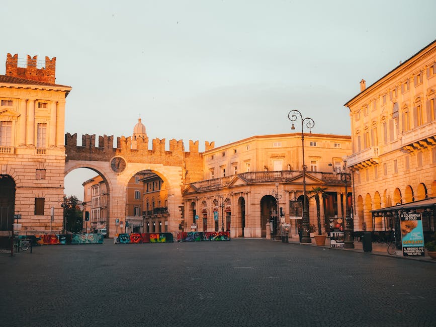 Arco medievale e palazzi illuminati dall'alba nella piazza di Parma