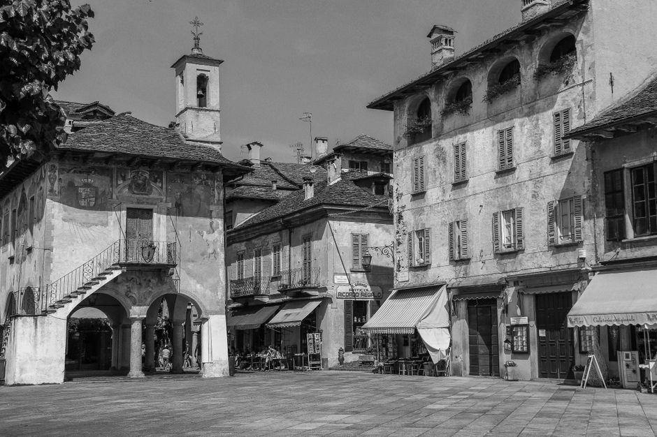 Piazza storica con edifici affrescati e portici in bianco e nero