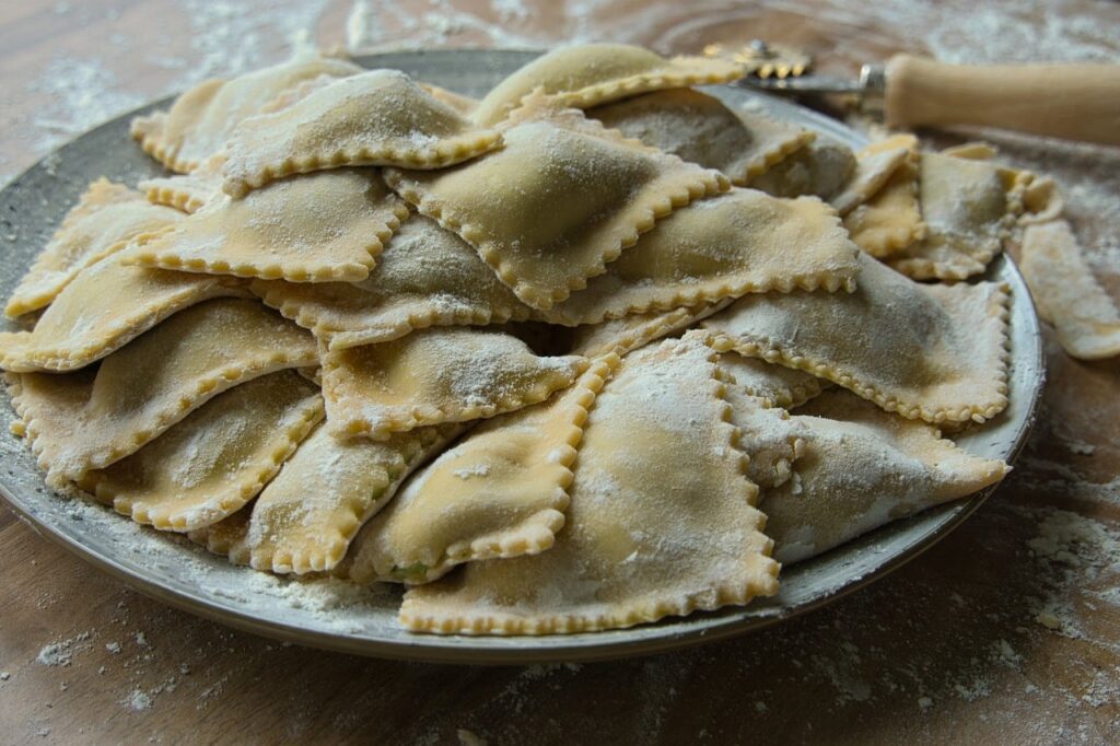 Stack of flour-dusted ravioli on a plate, typical of Parma