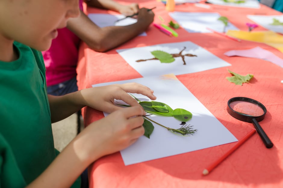 Enfants collant des feuilles lors d'un atelier nature au Parco del Taro
