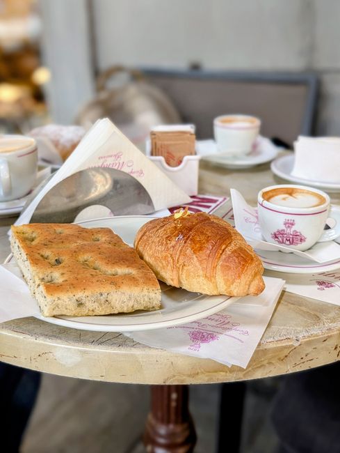 Colazione a base di cappuccino e cornetto in un bar di Parma