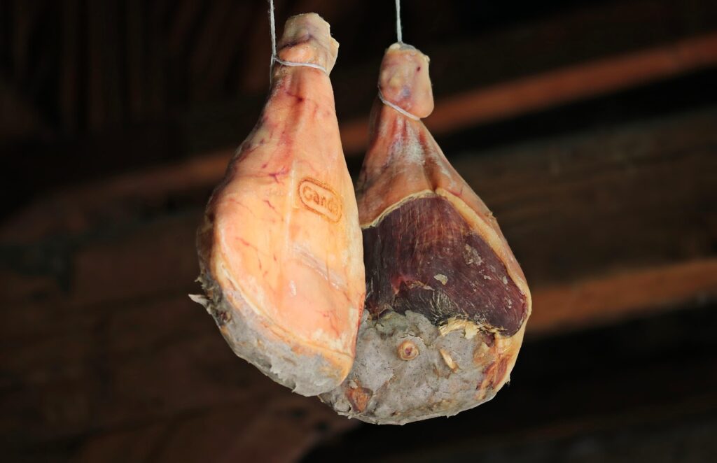 Deux jambons de Parme marqués suspendus dans un séchoir traditionnel