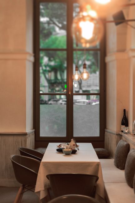 Ustawiony stolik przy oknie z wiszącymi żarówkami w restauracji w Parmie