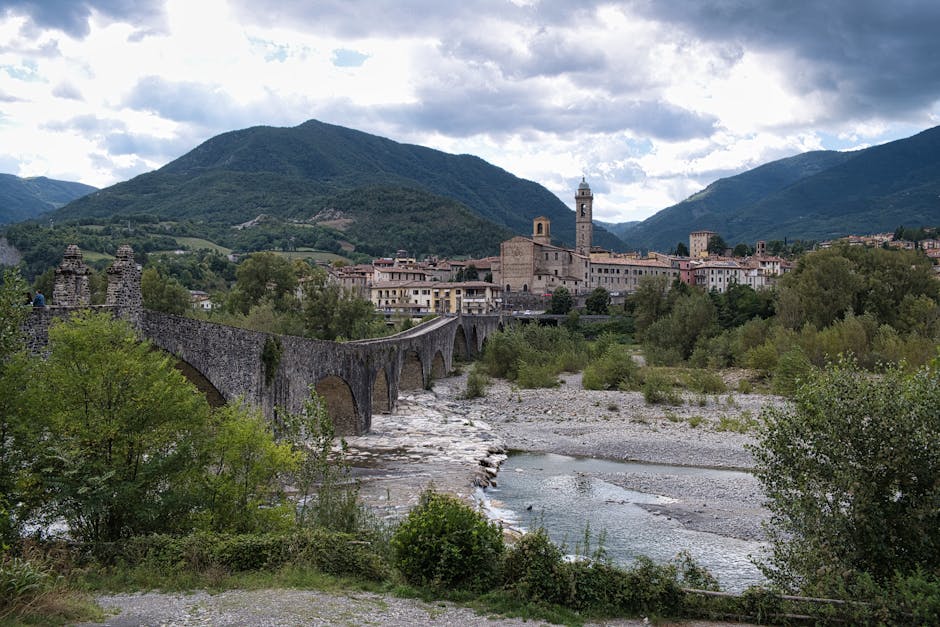 Pont médiéval en arches traversant la rivière, village niché au pied des montagnes