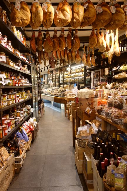 Feinkostladen in Parma mit zahlreichen hängenden Schinken und Regalen