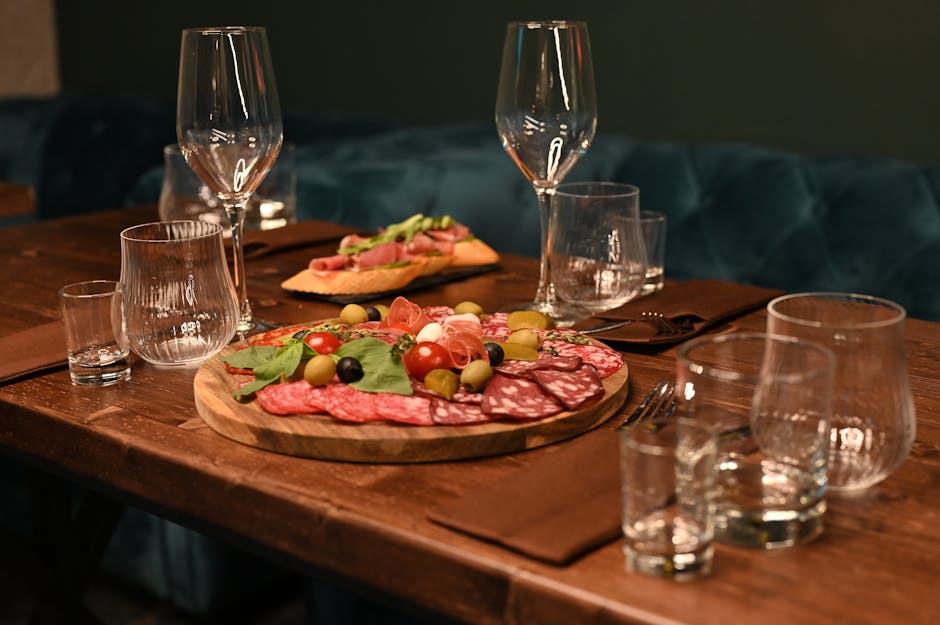 Wurstplatte mit Parma-Schinken und Weingläsern auf rustikalem Tisch