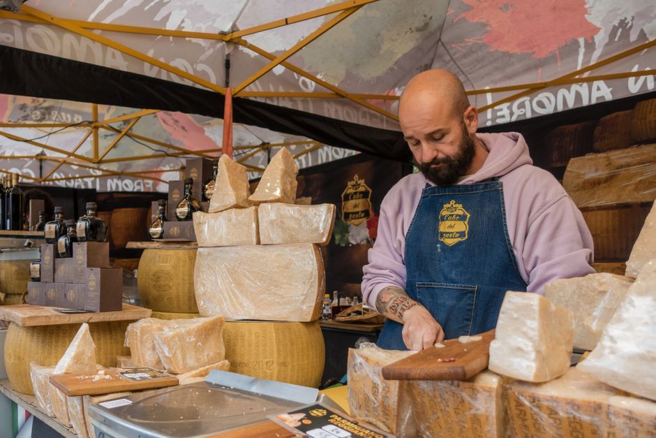 Artisan slicing Parmesan cheese at a Parma market