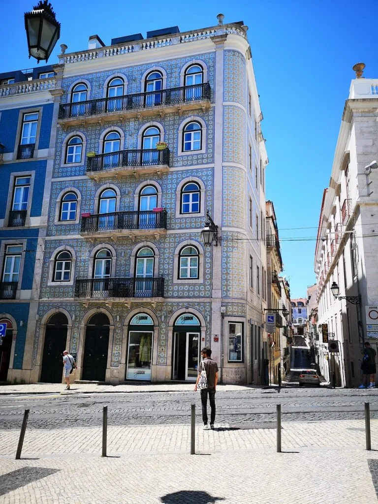 Jeune homme regardant une façade à azulejos typique de Lisbonne