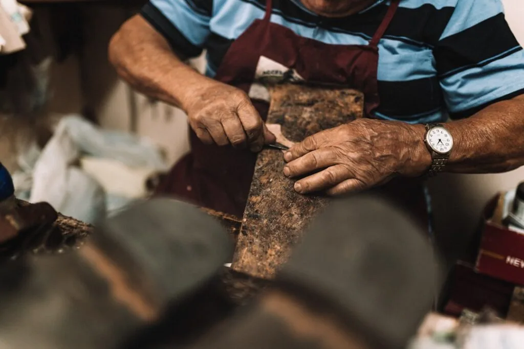 Mains d'un artisan cordonnier travaillant une semelle dans un atelier de Bergame