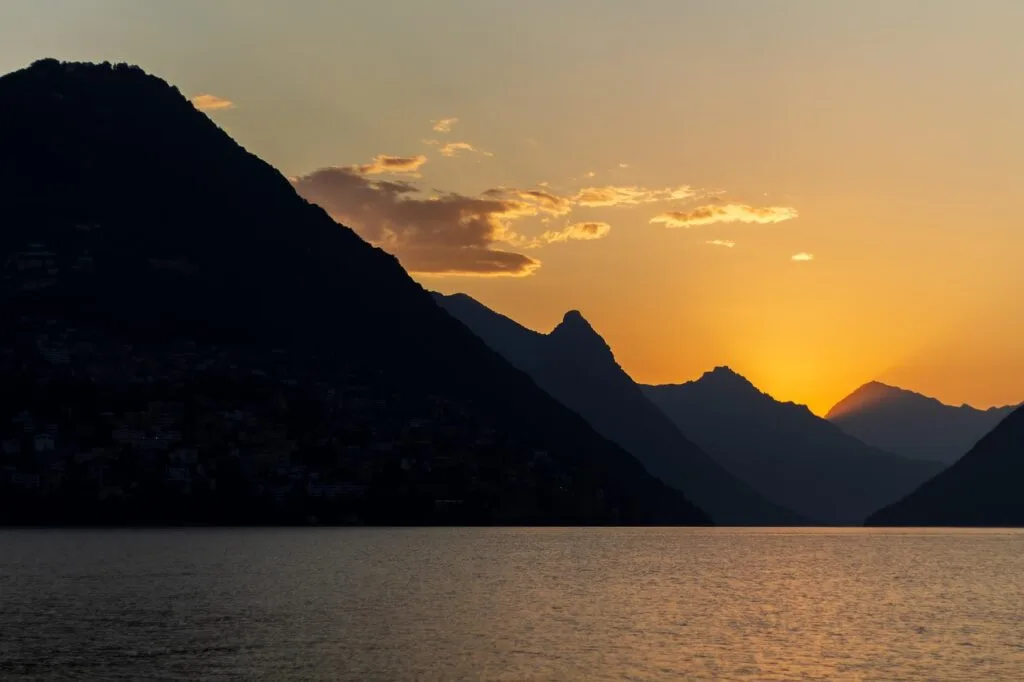 Coucher de soleil sur un lac, silhouettes montagneuses en arrière-plan