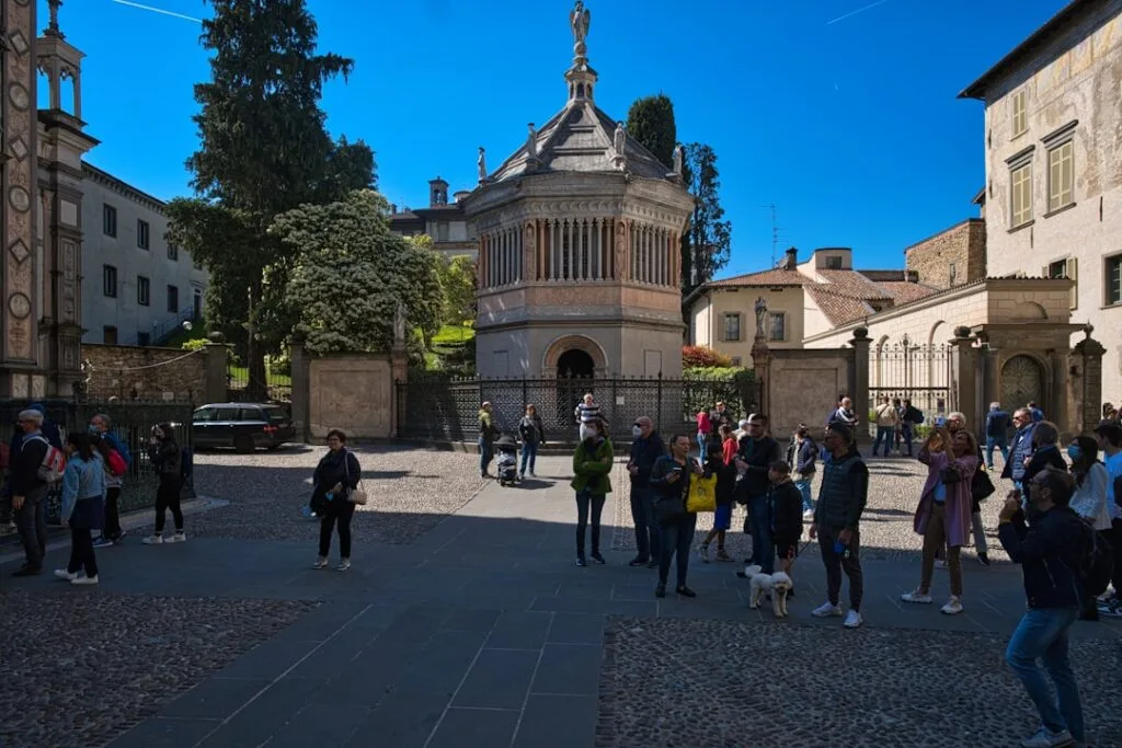 Baptistère octogonal et visiteurs sur la piazza devant la chapelle à Bergame.