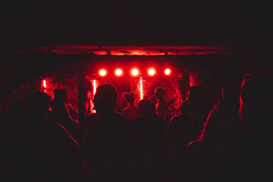 Silhouettes sous éclairage rouge dans un club rock bergamasque