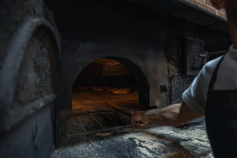 Boulanger à Bergame enfournant des pains dans un four à bois traditionnel