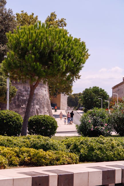 Promeneurs devant une tour et des buissons près des remparts de Bergame