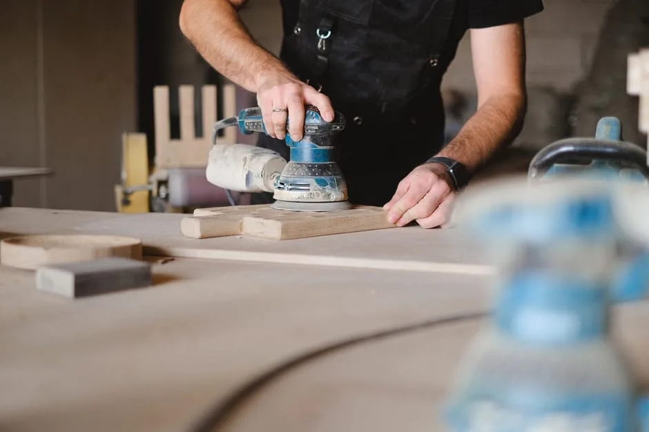 Artisan ponçant une planche en bois dans un atelier de Bergame