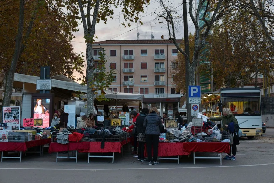 Marché en plein air à Bergame avec stands de vêtements et clients
