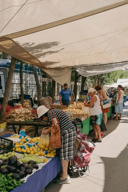 Clients fouillant des légumes sous des bâches au marché en plein air de Bergame