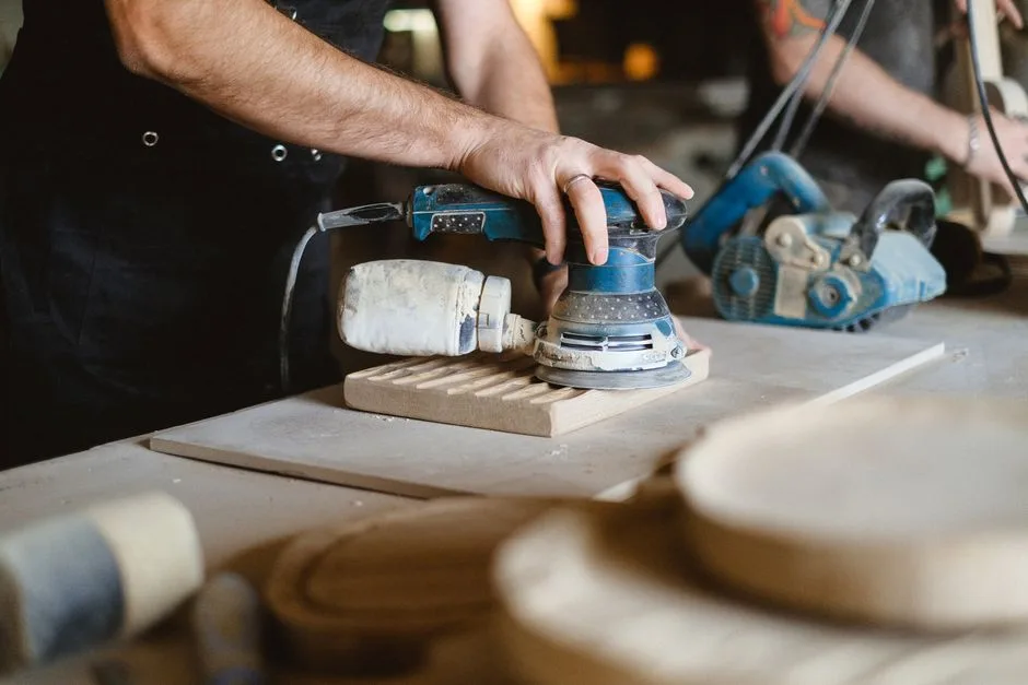 Mains d'artisan ponçant un plateau en bois dans un atelier à Bergame