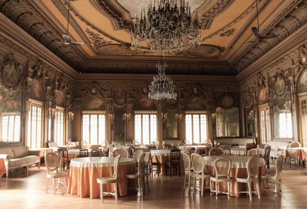 Grande salle ornée du château de Miramare avec lustres et tables