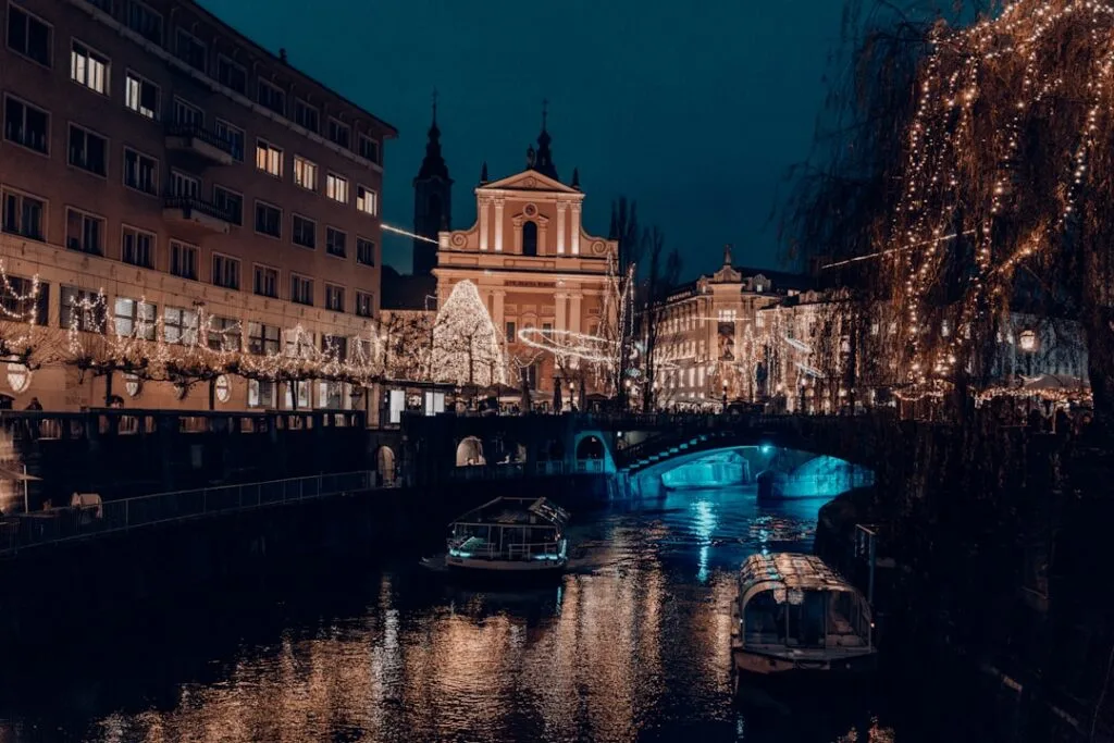 Canal illuminé avec petits bateaux et décorations de Noël à Ljubljana