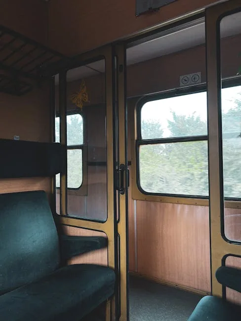 Banquettes vertes et portes vitrées d'un wagon, paysage flou par la fenêtre