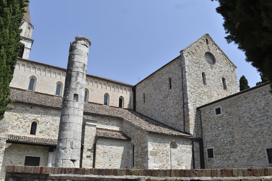 Façade en pierre de la basilique d'Aquileia avec colonne romaine
