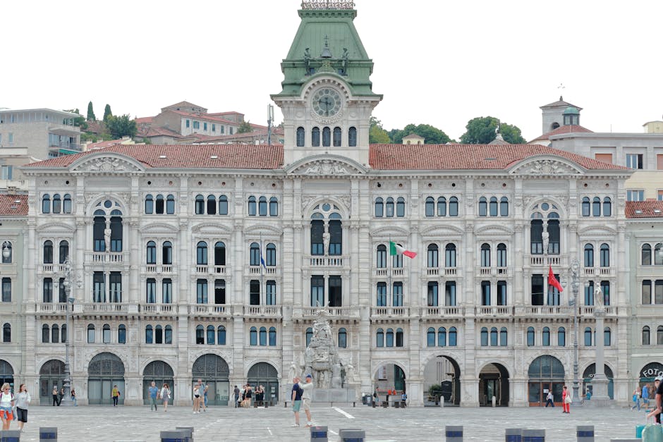 Façade sculptée du palais communal de Trieste avec fontaine et drapeaux