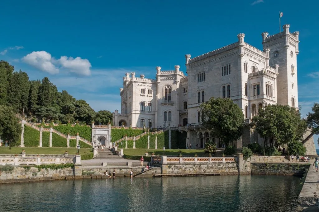 White Miramare Castle and terraced gardens beside Trieste's rocky coastline