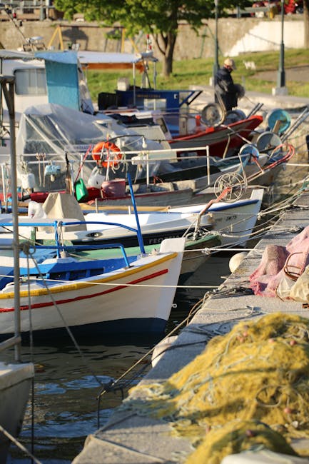 Barques de pêche colorées amarrées au quai, filets et matériel au premier plan