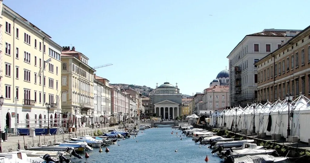 Canal de Trieste bordé de bateaux et façades colorées, temple visible
