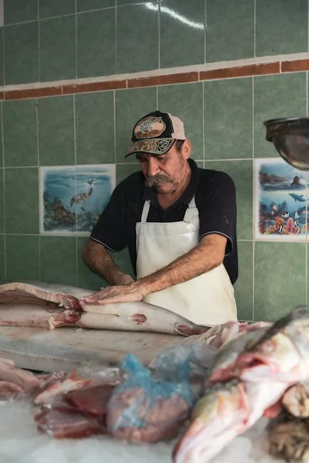 Poissonnier en tablier en train de fileter un gros poisson dans une échoppe de Trieste