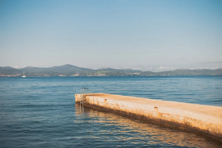 Jetée basse à Trieste avec échelle plongeant dans la mer calme
