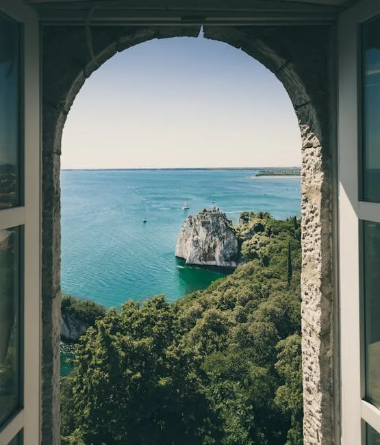 Vue encadrée par une arcade sur crique rocheuse et la mer à Trieste