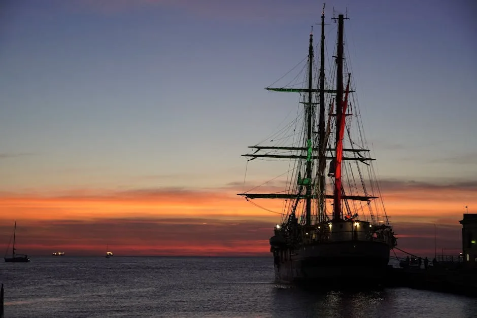 Grand trois-mâts silhouetté au coucher de soleil dans le port de Trieste