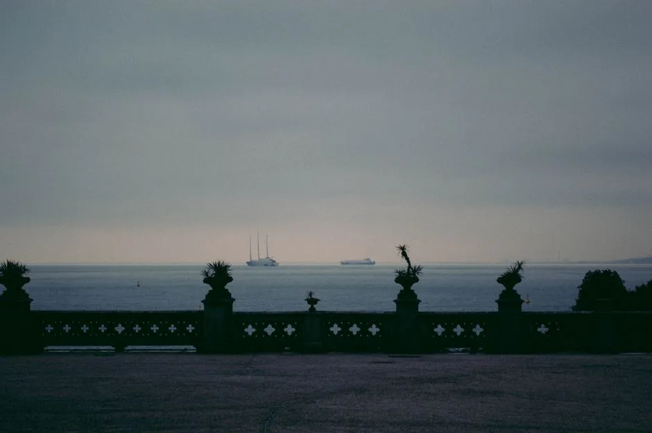 Terrasse en pierre à Trieste, balustrade sombre et navires au large