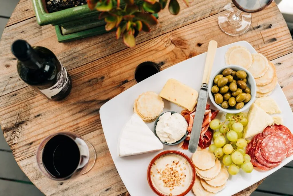 Assiette de fromages, charcuterie et olives accompagnée d'un verre de vin