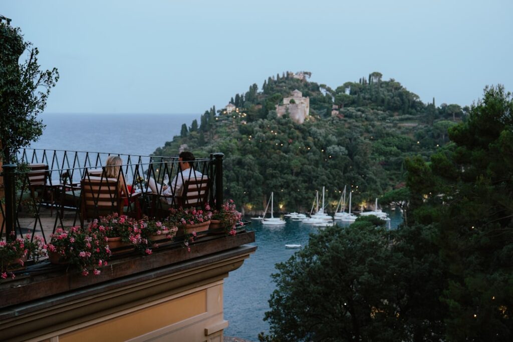 Couple dining on balcony overlooking marina and hillside in Îles Éoliennes