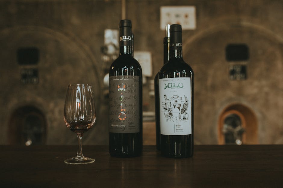 Two wine bottles and glass on wooden bar at Îles Éoliennes winery