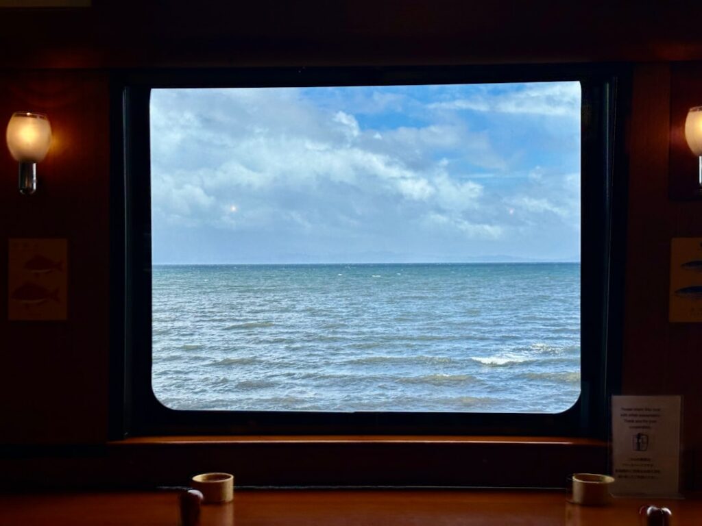 Vue sur la mer bleue encadrée par une fenêtre de ferry vers les Îles Éoliennes