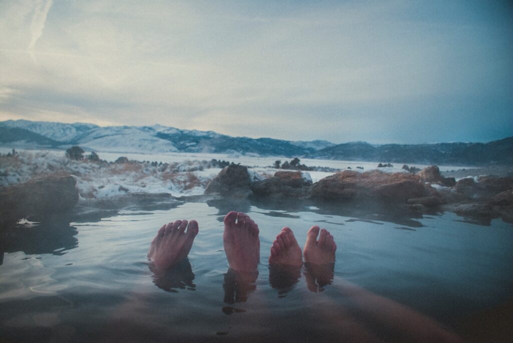 Two pairs of feet floating in warm spring with mountains, Îles Éoliennes