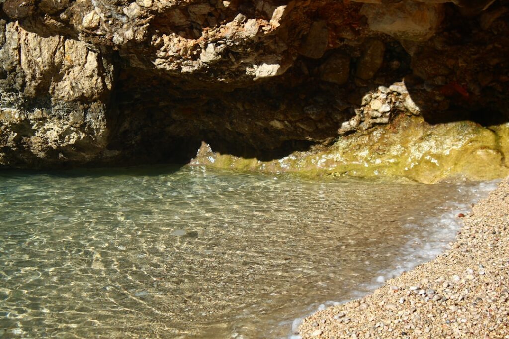 Crique de galets, eau cristalline et grotte rocheuse, Îles Éoliennes