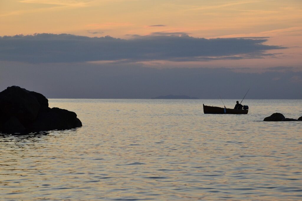 Silhouette of a fisherman in a small boat at sunset
