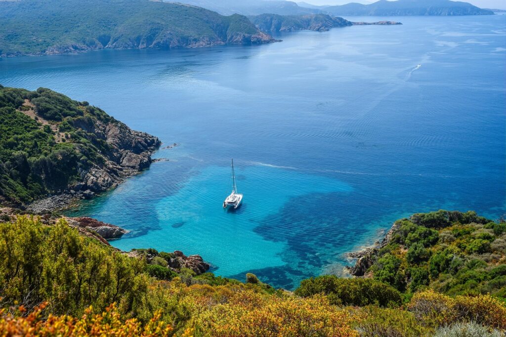 Sailboat anchored in a turquoise cove on Îles Éoliennes cliffs