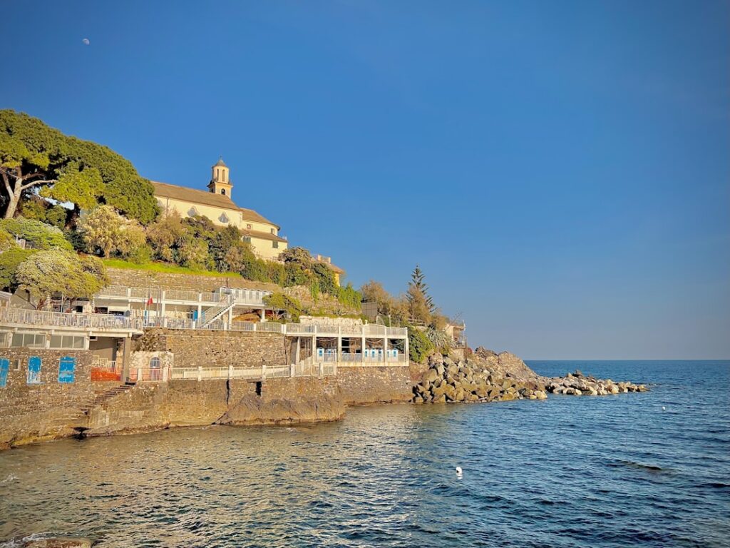 Sunlit hilltop church and seawall terraces overlooking the Aeolian Islands shoreline